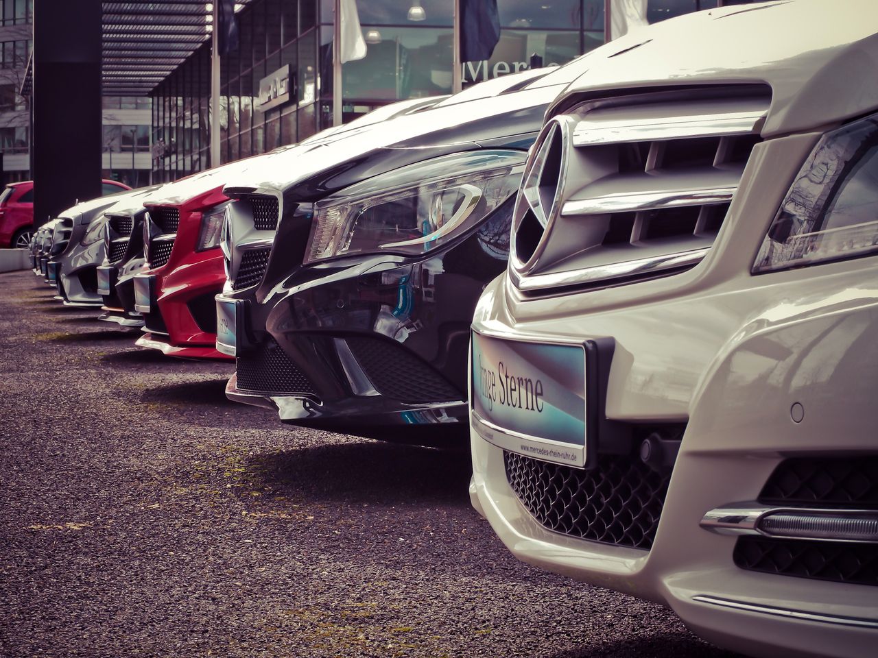 About Luxury cars lined up at an outdoor dealership, showcasing sleek designs.